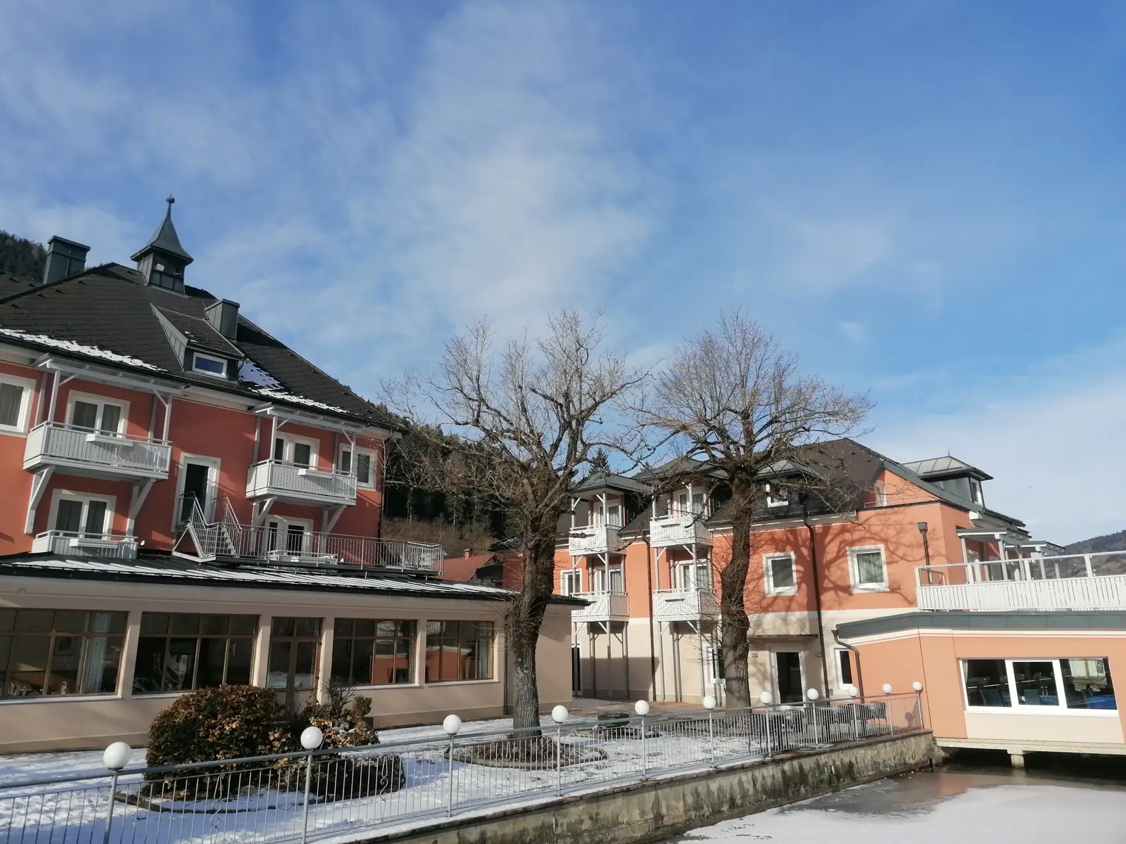 Strandhotel Burgstaller im Winter - Sonne auf der verschneiten Fassade am Brennsee