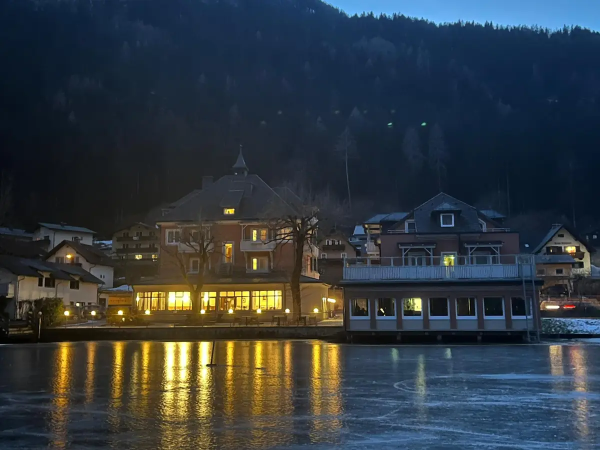 Das beleuchtete Hotel am Winterabend, gespiegelt im Eis